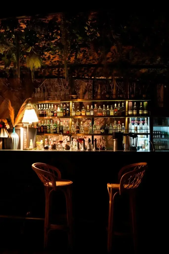 Bar ambiance tamisé avec mur végétal et bouteilles en fond dans le restaurant rôtisserie de la paix à Marrakech Quartier Guéliz | Alba Photographe Restaurant Toulouse