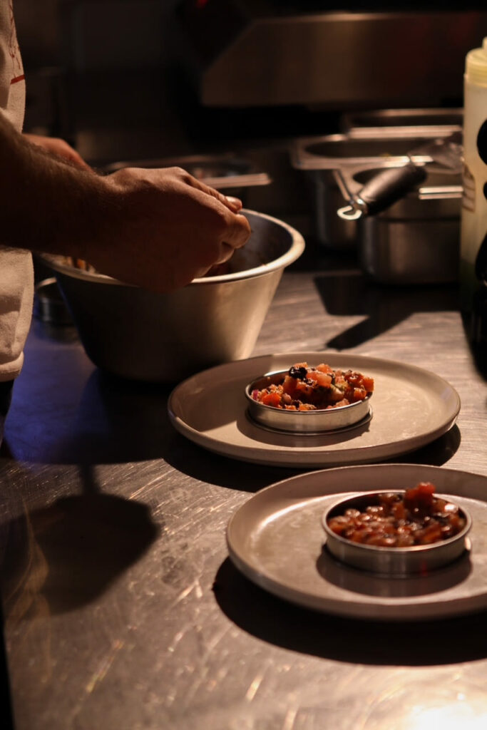 Dressage d'un plat, ambiance tamisée, par le chef en cuisine dans le restaurant Maison Bagarre